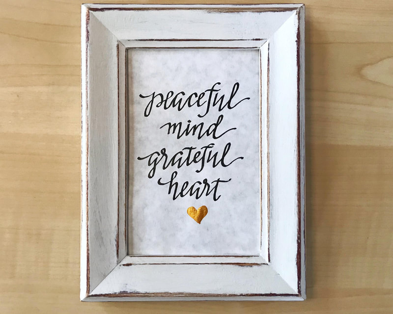 Hand Lettered Calligraphy Quote in black and gold ink, "Peaceful mind Grateful heart"
